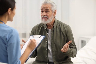 Photo of Elderly patient talking with nurse in hospital