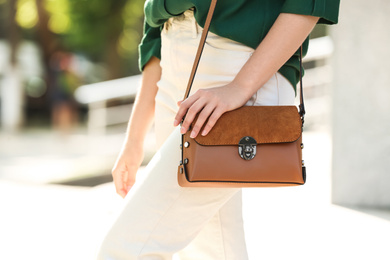 Photo of Young woman with stylish leather bag outdoors on summer day, closeup