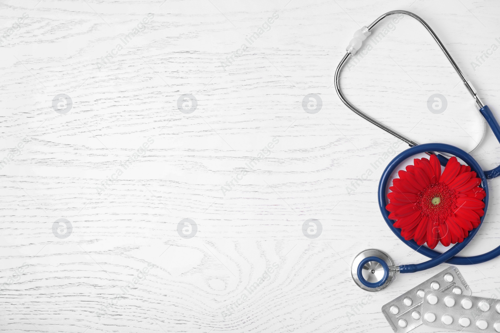 Photo of Flat lay composition with stethoscope, pills and flower on white wooden background, space for text. Gynecology concept