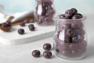 Photo of Jar of fresh acai berries on stone table, closeup. Space for text