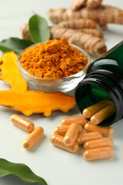 Photo of Aromatic turmeric powder, pills and raw roots on white table, closeup