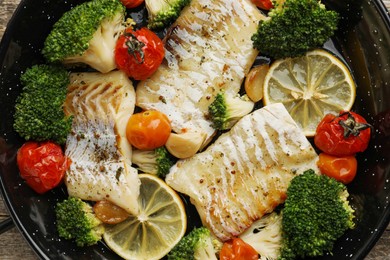 Photo of Tasty cod cooked with vegetables in frying pan. top view