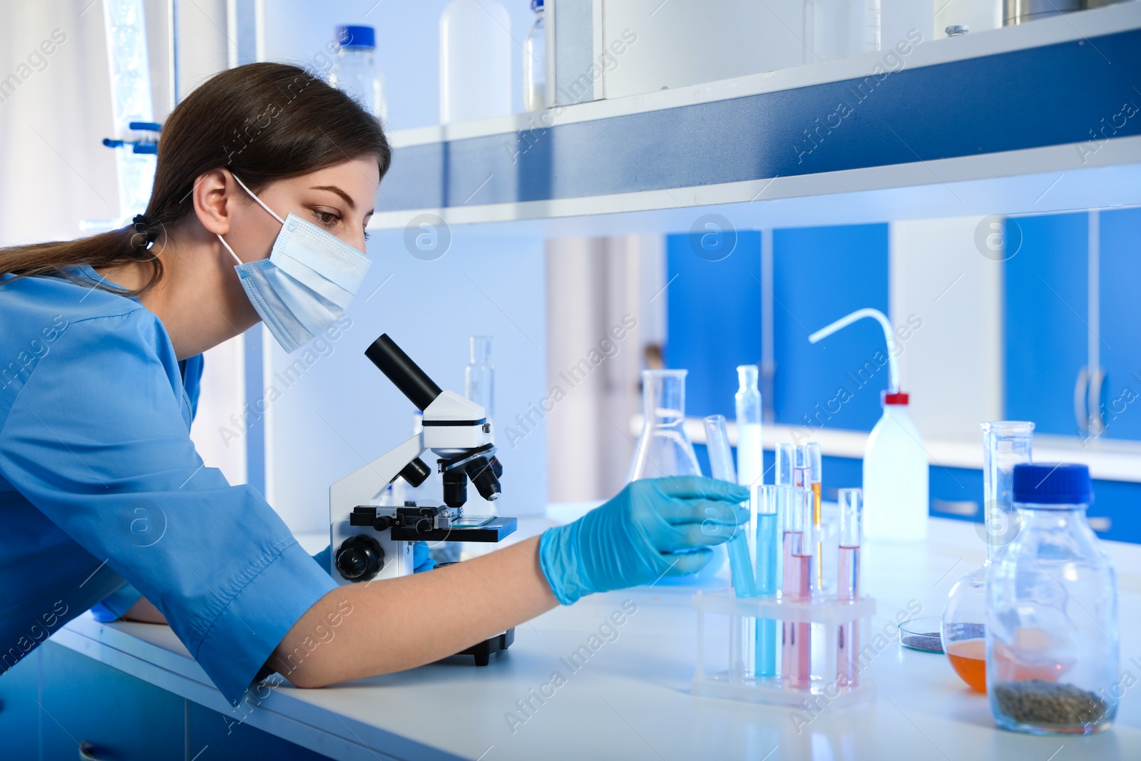 Photo of Scientist working with microscope and test tubes indoors. Laboratory analysis