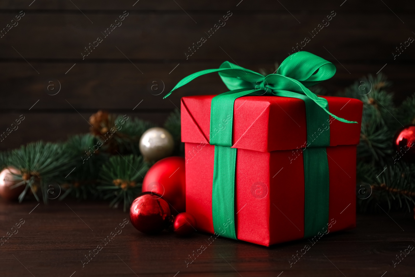 Photo of Christmas gift box with green bow and festive decor on wooden table. Space for text