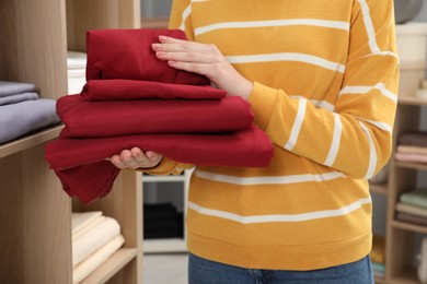 Photo of Woman with stack of bed linens in shop, closeup
