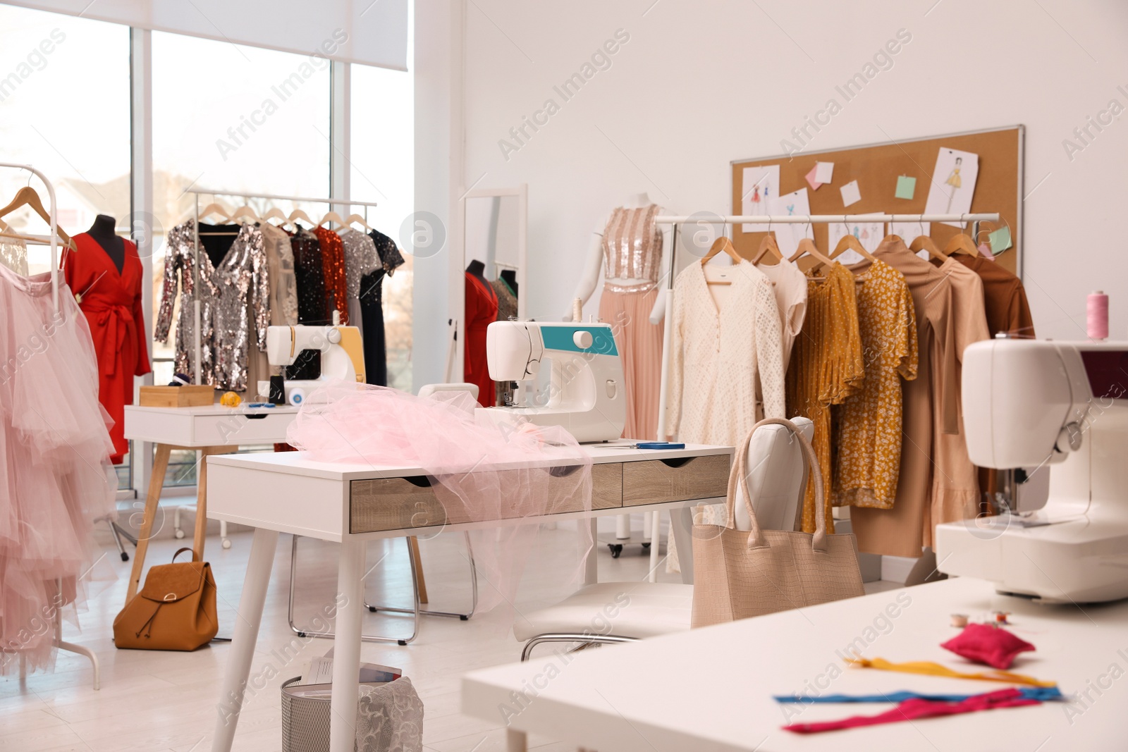 Photo of Dressmaking workshop interior with stylish female clothes and equipment