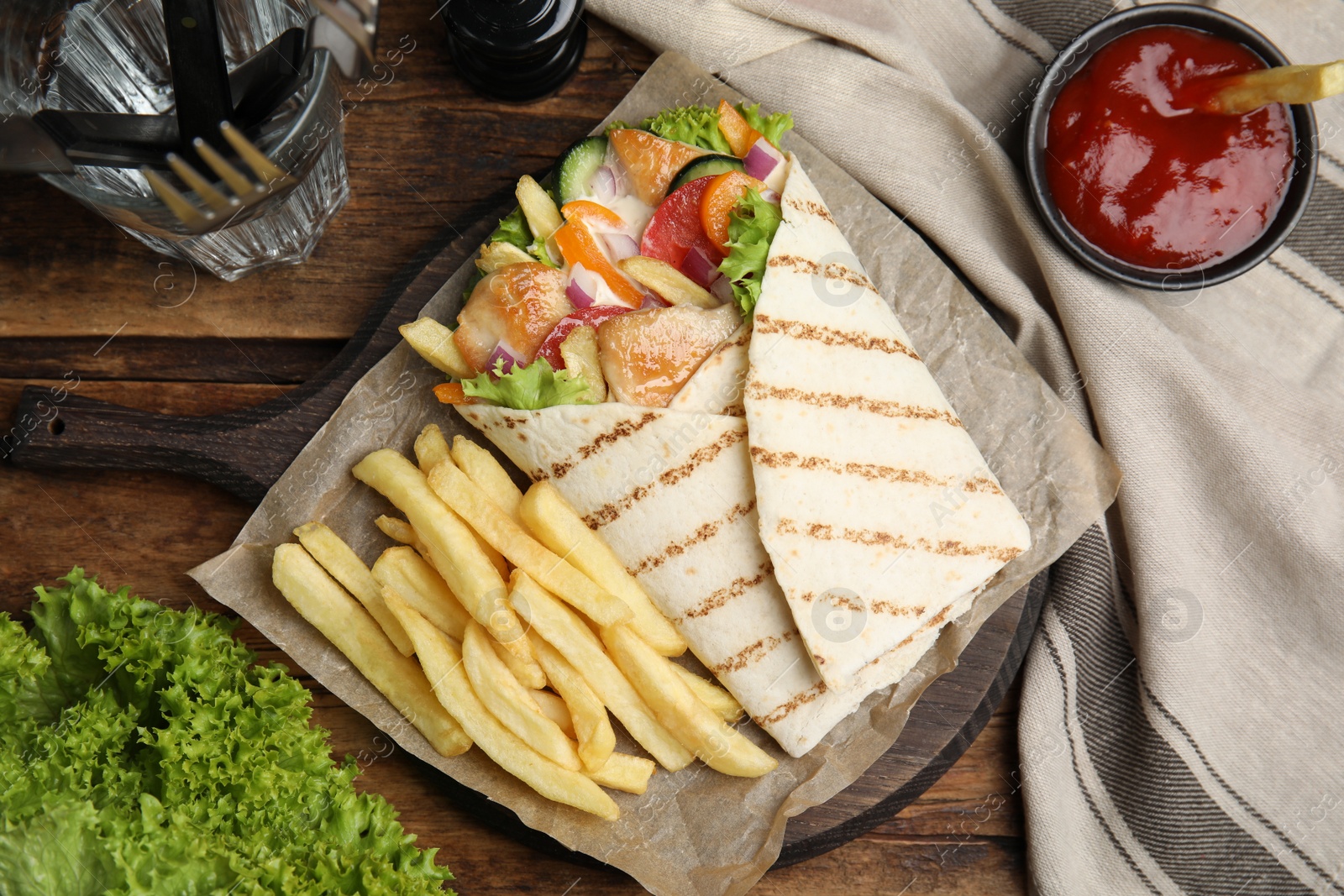 Photo of Delicious chicken shawarma and French fries served on wooden table, flat lay