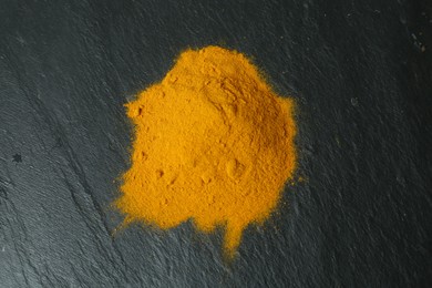 Photo of Turmeric powder on black textured table, top view
