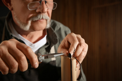 Man sewing piece of leather in workshop, closeup