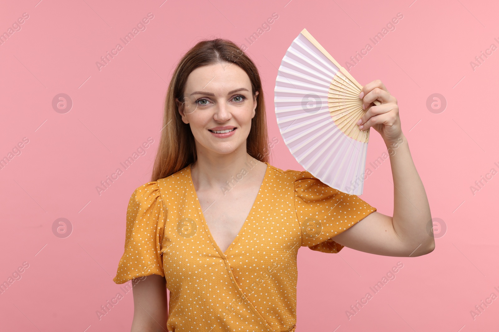 Photo of Happy woman with hand fan on pink background