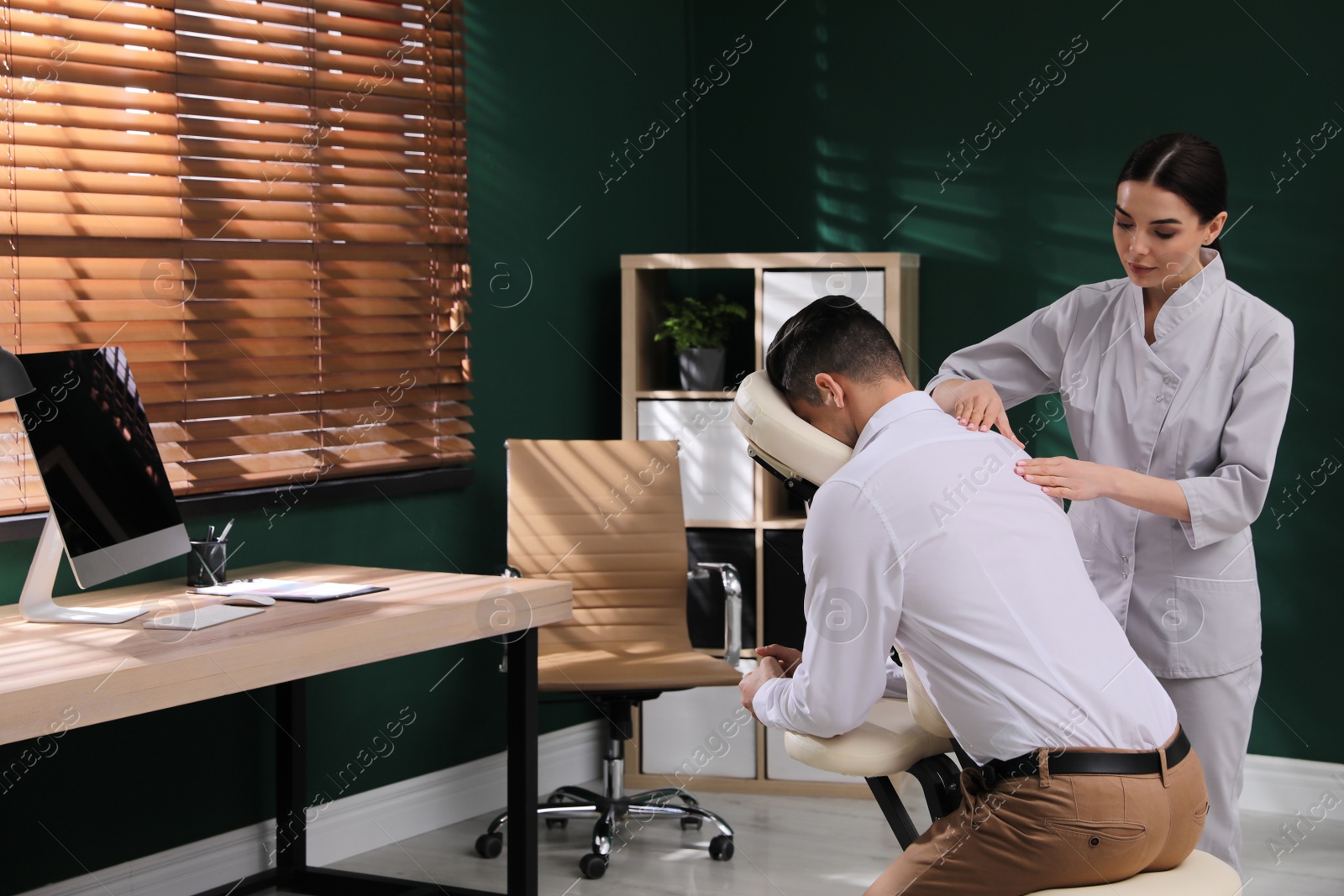 Photo of Man receiving massage in modern chair indoors