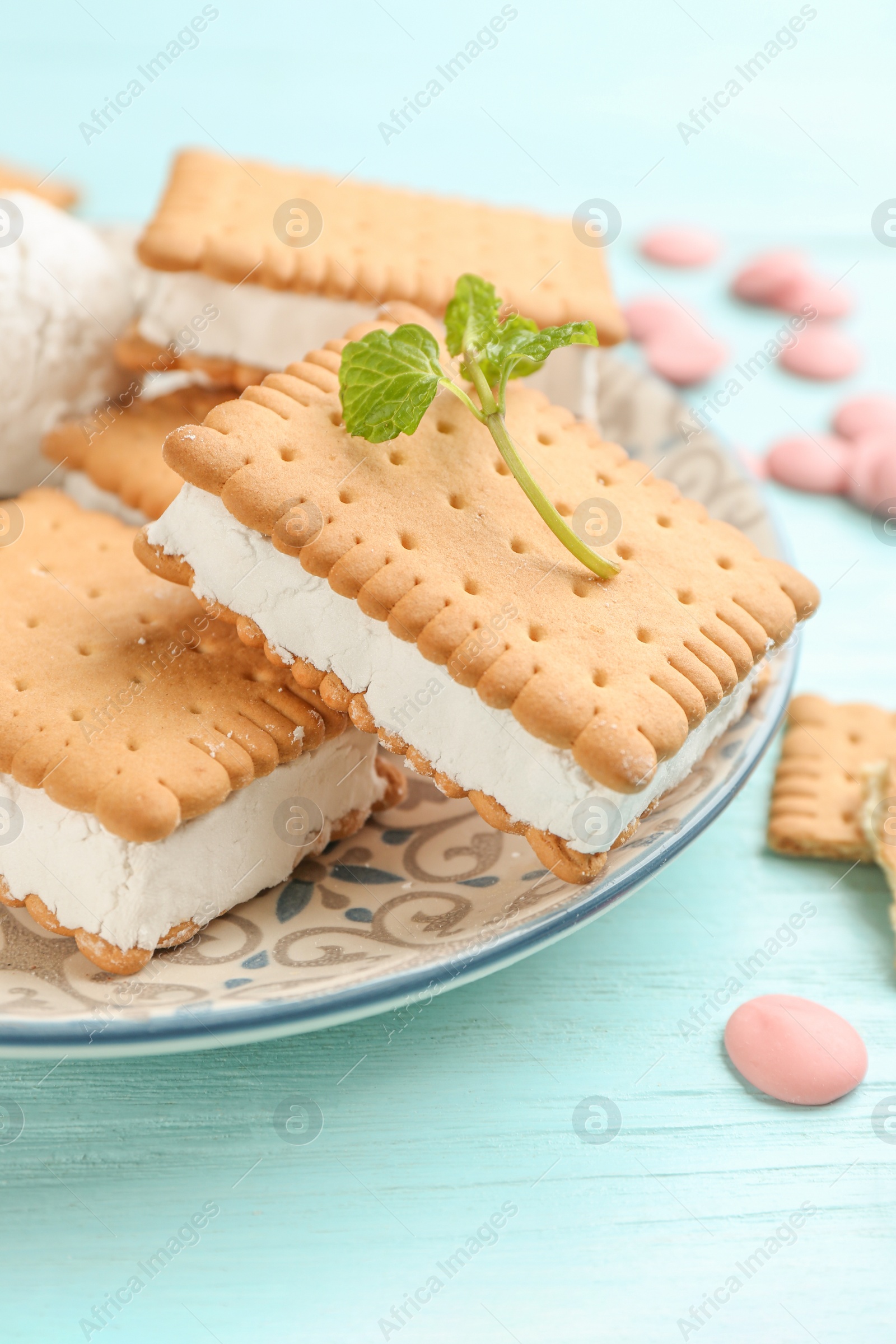 Photo of Sweet delicious ice cream cookie sandwiches on light blue wooden table