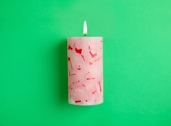 Alight scented wax candle on color background