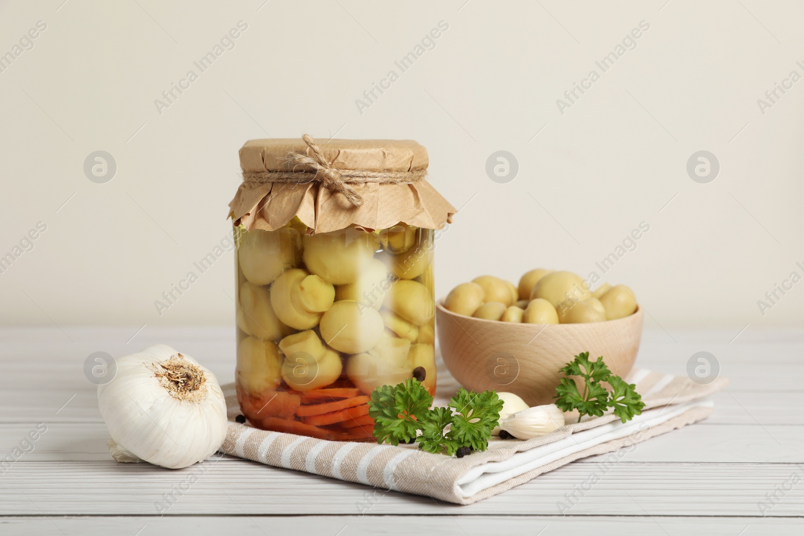 Photo of Tasty pickled mushrooms and spices on white wooden table