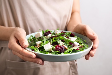 Woman with fresh delicious beet salad on light background, closeup