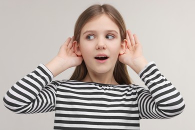 Little girl with hearing problem on grey background