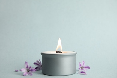 Beautiful candle with wooden wick and flowers on light background