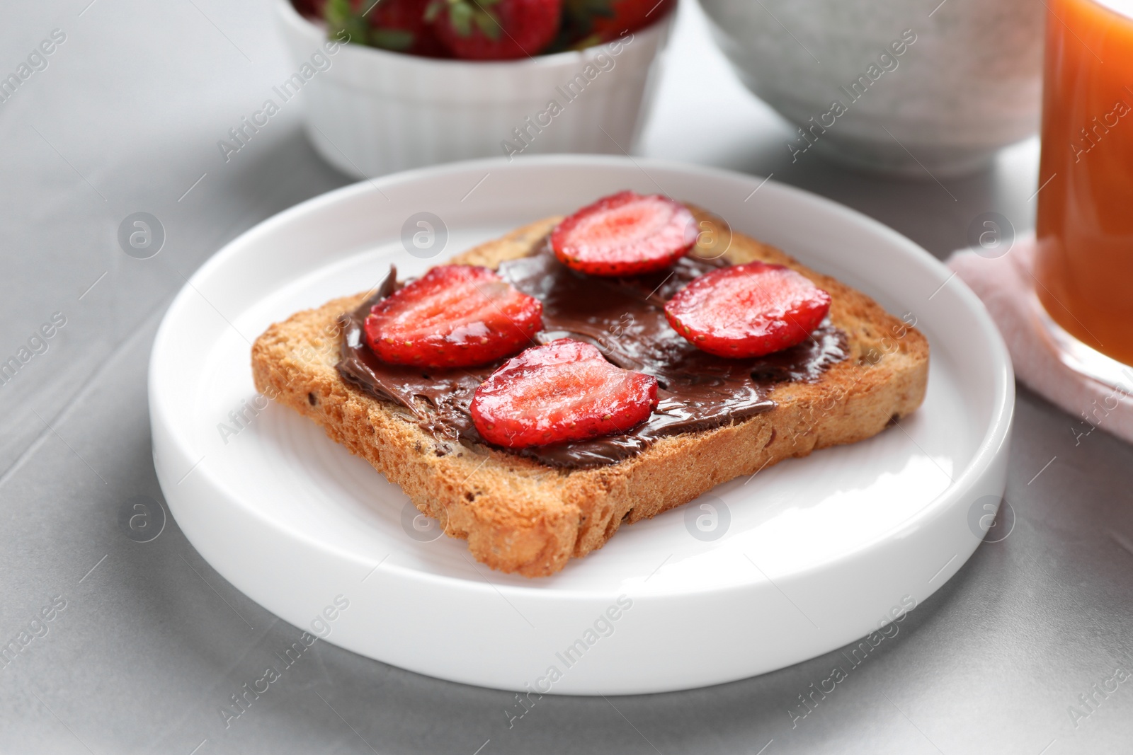 Photo of Toast with chocolate spread and strawberries on light grey table, closeup. Healthy breakfast