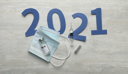 Photo of Flat lay composition with coronavirus vaccine and number 2021 on white background