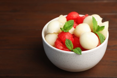 Bowl with melon and watermelon balls on wooden table