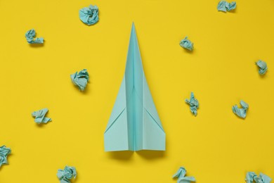 Photo of Flat lay composition with handmade plane and many crumpled pieces of paper on yellow background