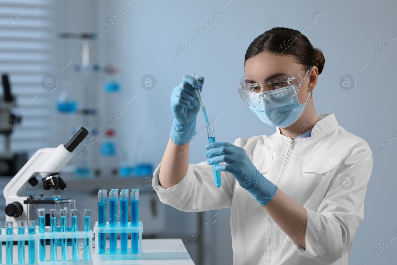 Photo of Scientist taking sample with dropper from test tube in laboratory