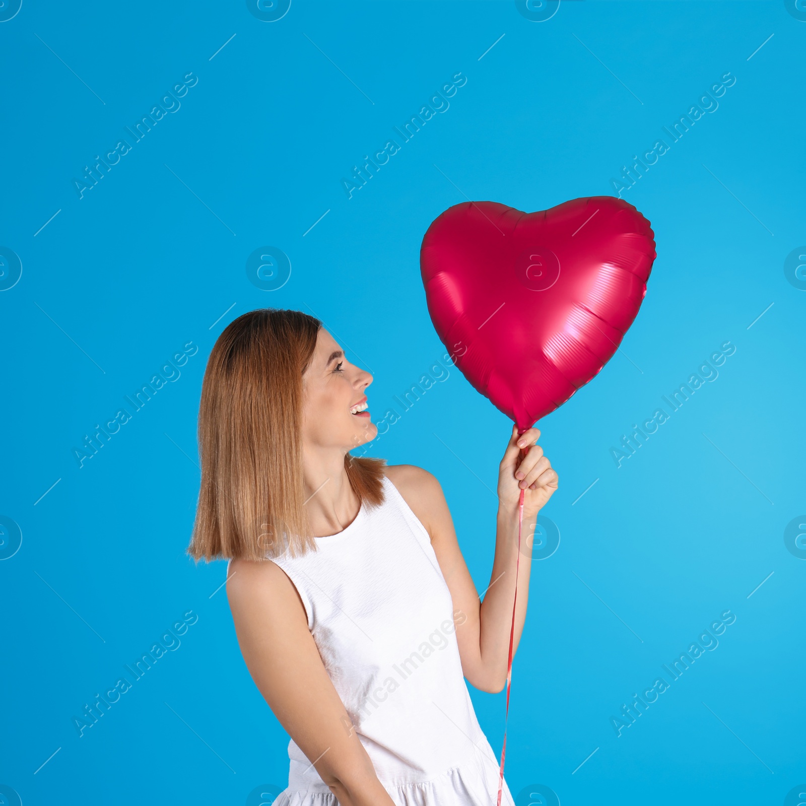 Photo of Portrait of woman with heart shaped balloon on color background