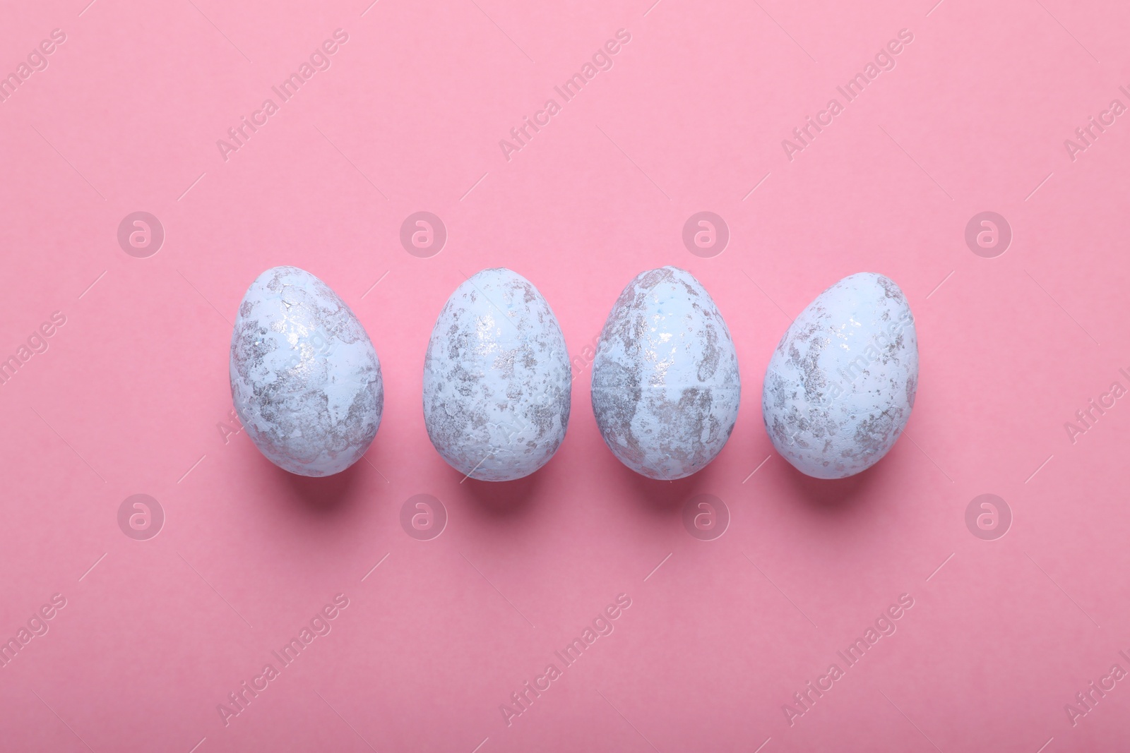 Photo of Many painted Easter eggs on pink background, flat lay