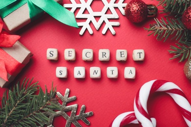 Photo of Flat lay composition with festive decor, presents and words Secret Santa on red background