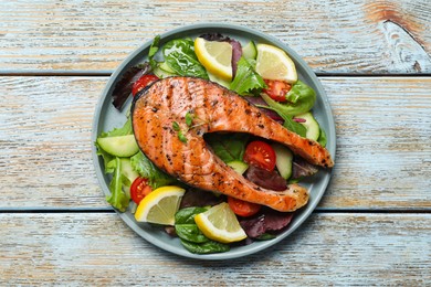 Photo of Tasty salmon steak with lemon and vegetables on white wooden table, top view