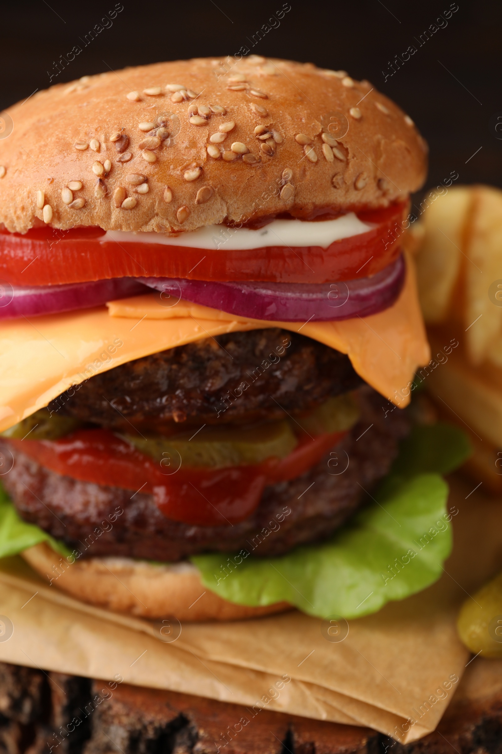 Photo of Tasty cheeseburger with patties on tree stump, closeup