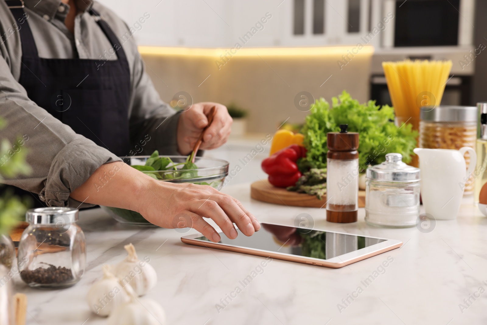 Photo of Man using tablet while cooking at countertop in kitchen, closeup