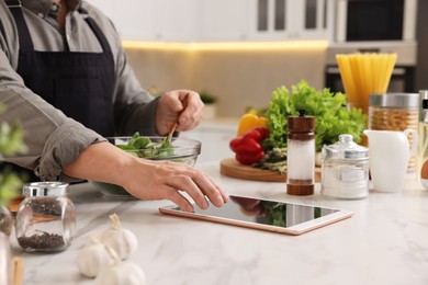 Man using tablet while cooking at countertop in kitchen, closeup