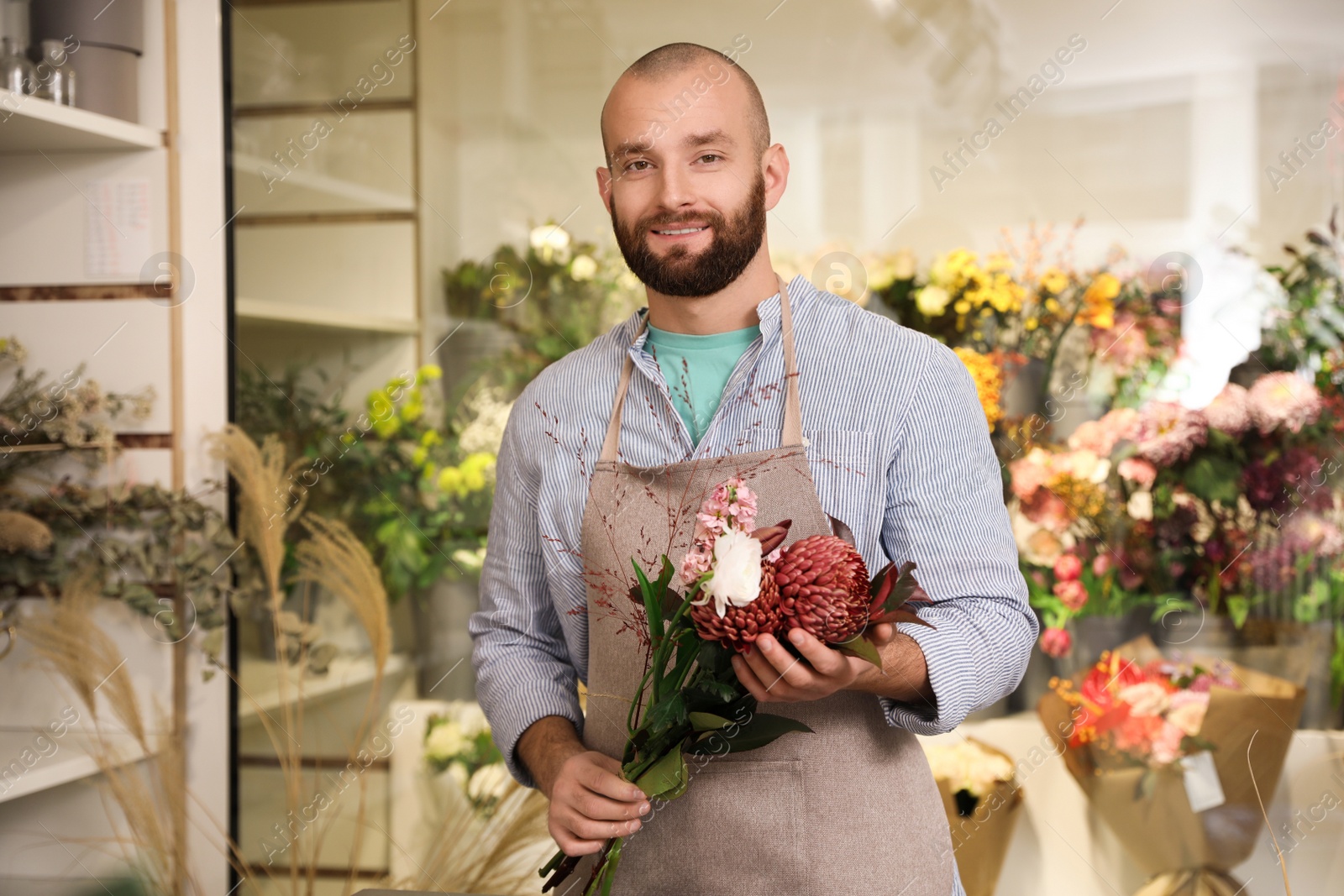 Photo of Professional florist with bouquet of fresh flowers in shop