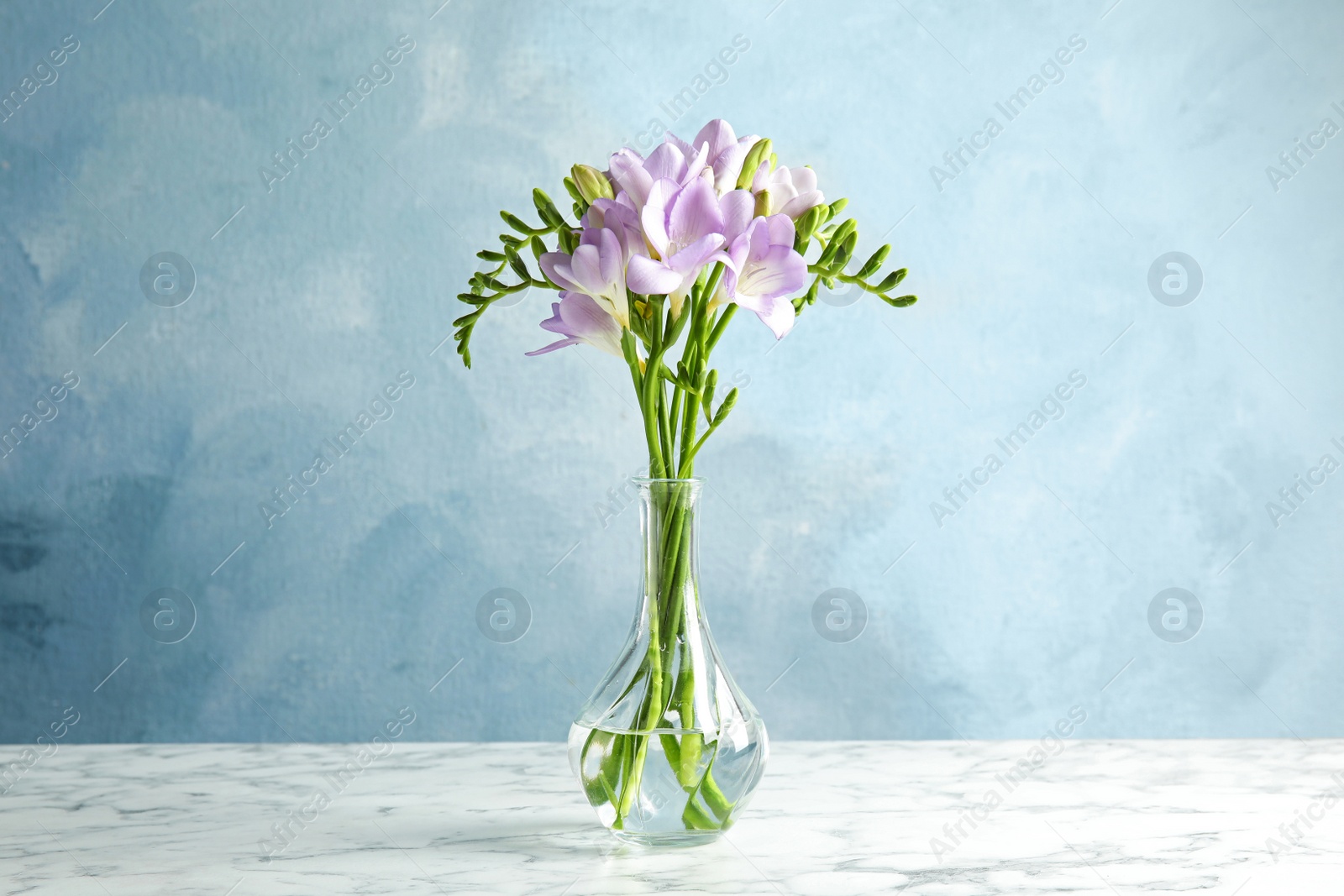 Photo of Bouquet of fresh freesia flowers in vase on table