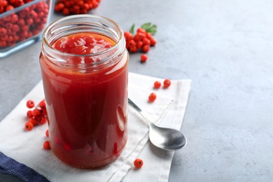 Delicious rowan jam in glass jar on grey table. Space for text