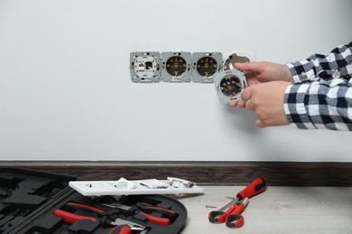 Electrician with screwdriver repairing power sockets indoors, closeup