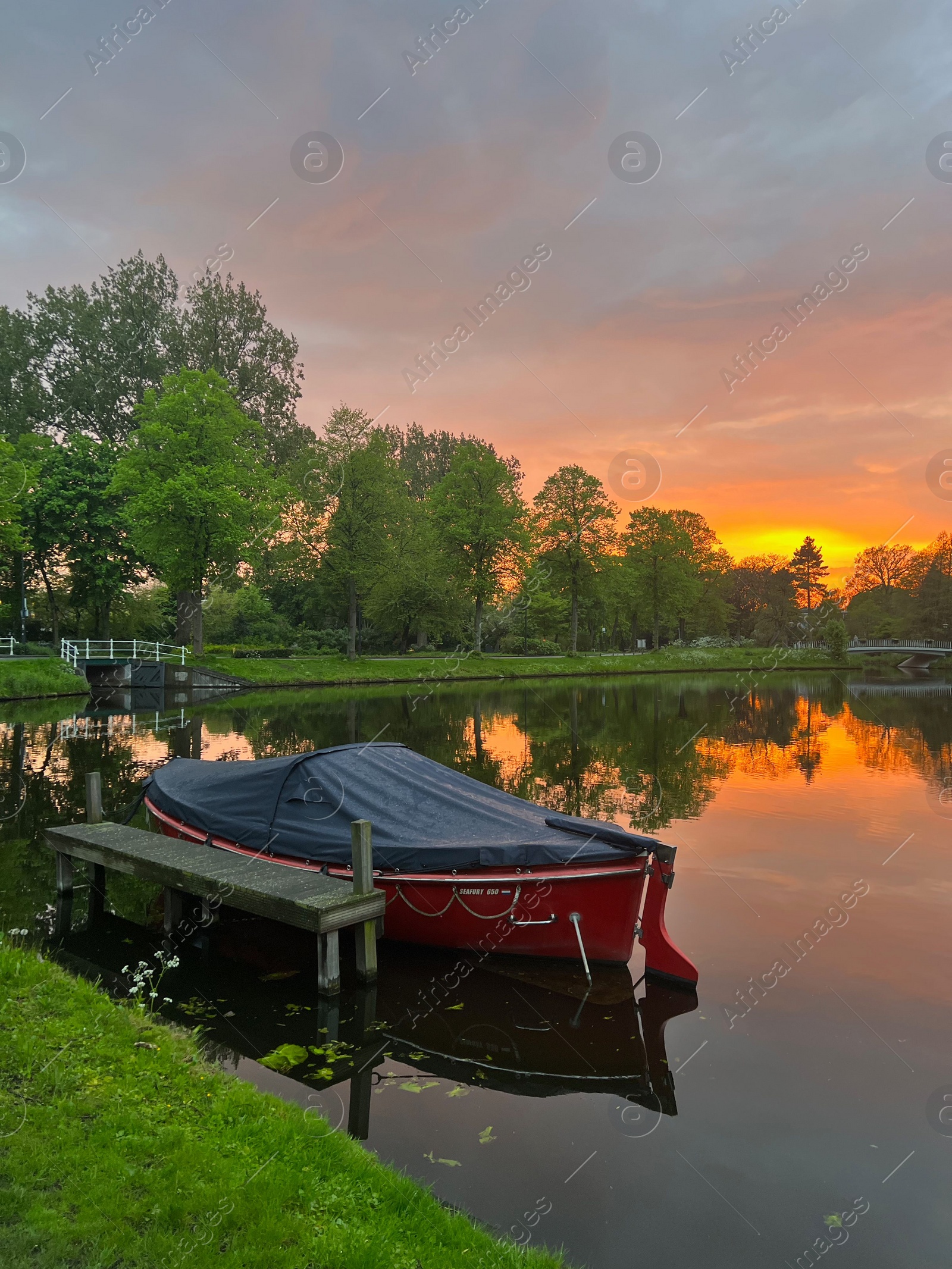 Photo of Scenic view of pond with moored boat at sunset