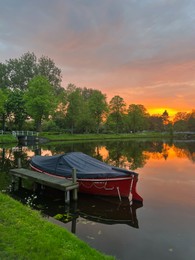 Scenic view of pond with moored boat at sunset