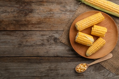 Photo of Flat lay composition with tasty sweet corn cobs on wooden background