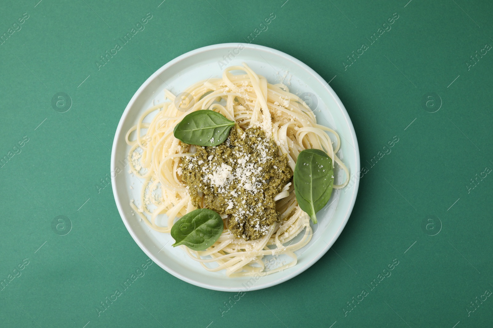 Photo of Tasty pasta with spinach, cheese and sauce on green table, top view