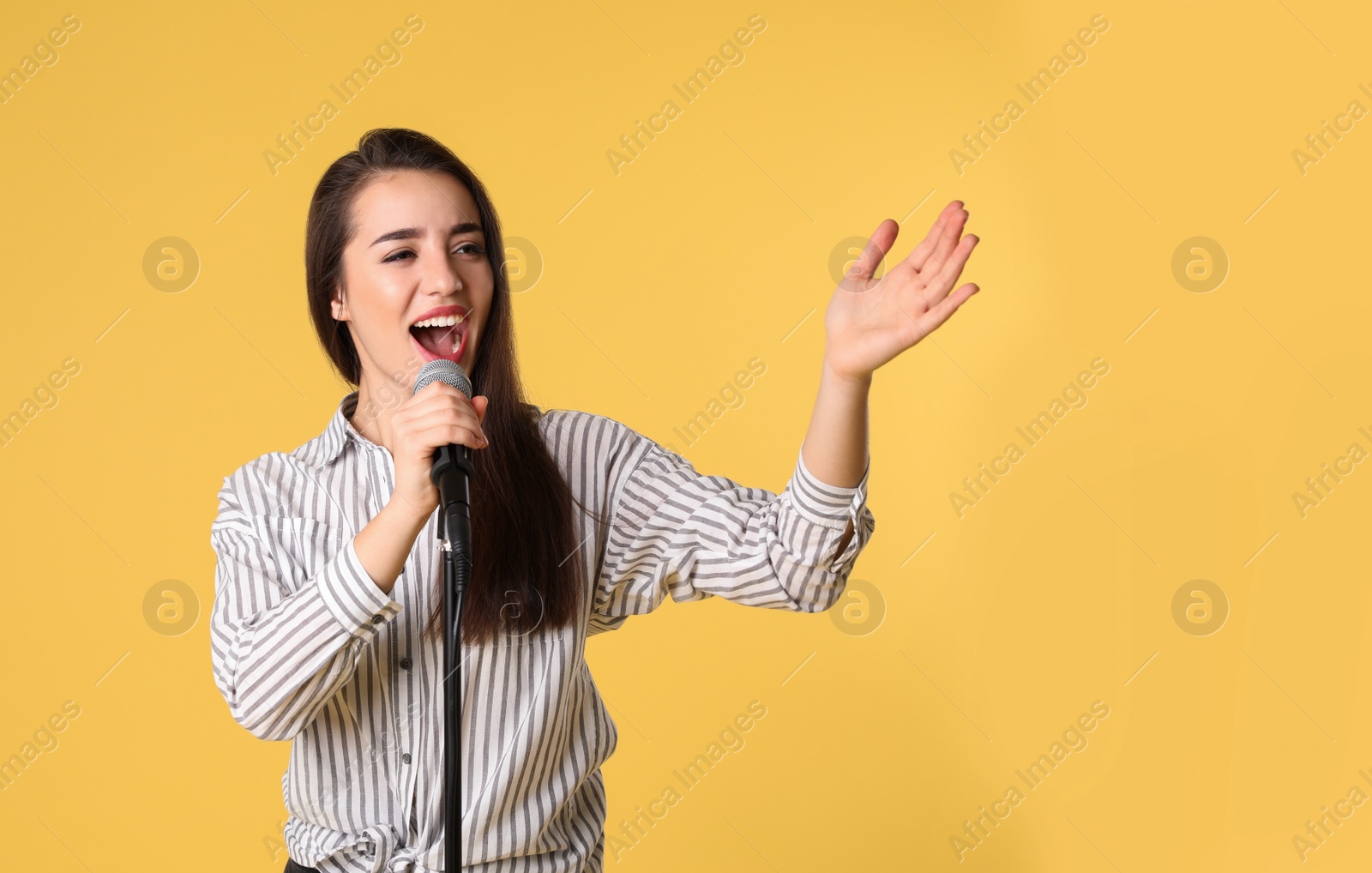 Photo of Young woman wearing casual clothes singing in microphone on color background