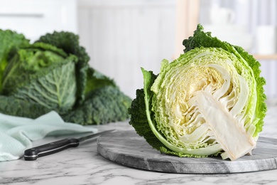 Photo of Half of fresh green savoy cabbage on white marble table