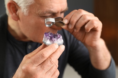 Photo of Male jeweler evaluating semi precious gemstone in workshop, closeup