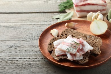 Tasty salt pork with rye bread and dill on wooden table, space for text