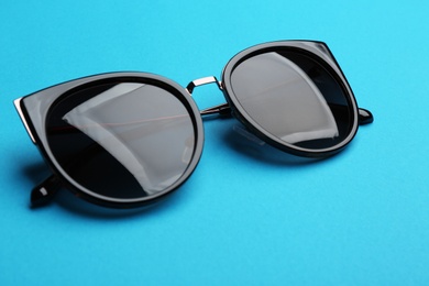 Stylish sunglasses on blue background. Fashionable accessory