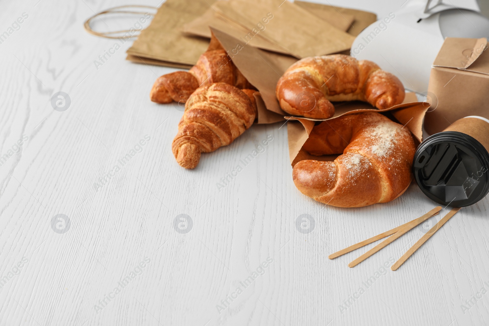 Photo of Paper bags with pastry and takeaway food on light table. Space for text