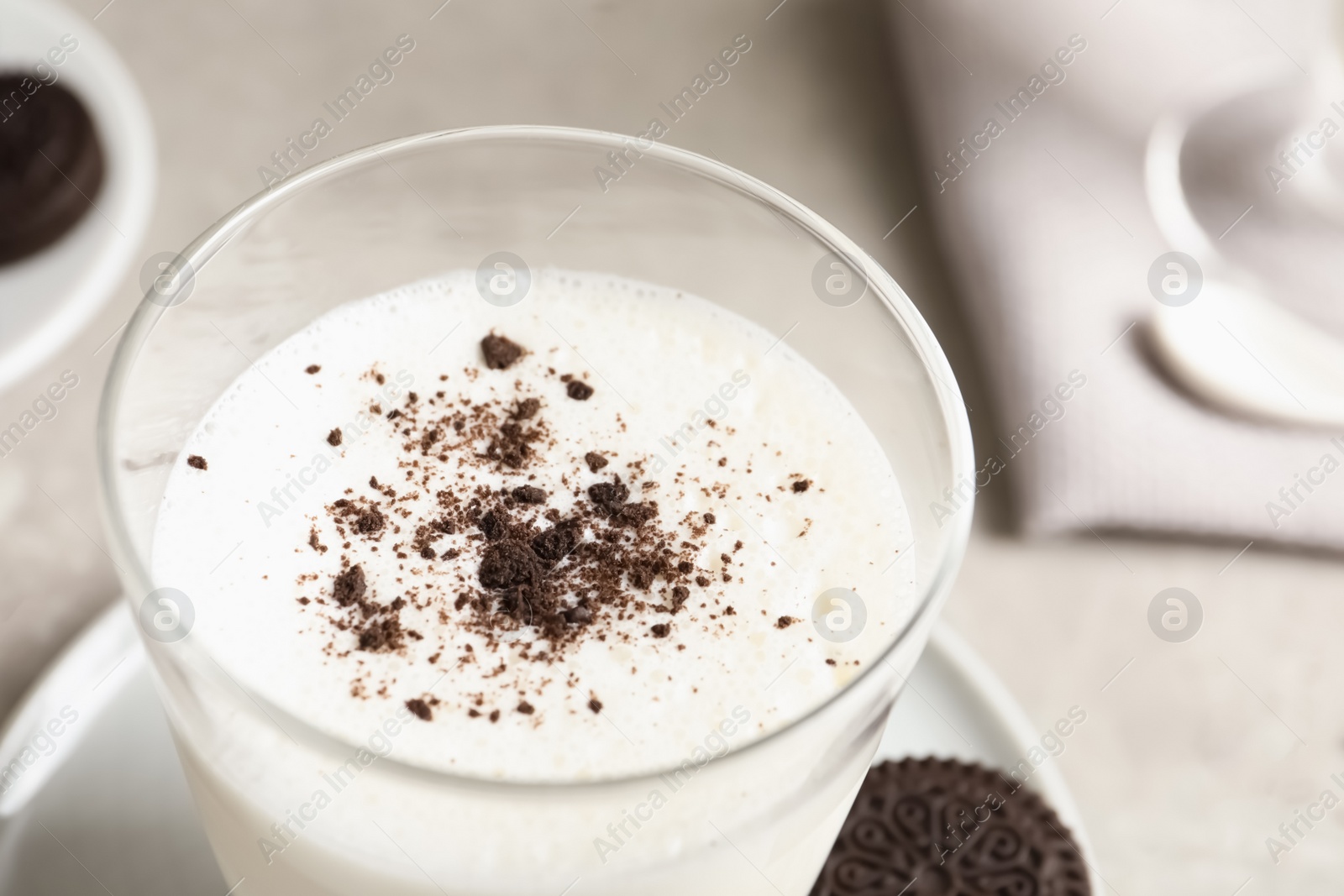 Photo of Glass of milk with chocolate cookie crumbs on table, closeup