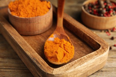 Photo of Spoon and bowl with saffron powder on wooden table, closeup