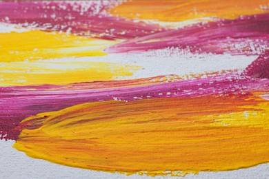 Photo of Strokes of colorful oil paints on white canvas, closeup